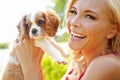 Too cute for words. Portrait of a happy beautiful blonde holding up an adorable puppy in the outdoors. Royalty Free Stock Photo