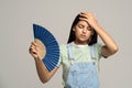 Sweaty teenage girl touching forehead using paper fan suffer from heat cooling in hot summer weather Royalty Free Stock Photo