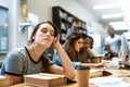 Too lazy to learn today. Shot of a young woman looking tired while studying in a college library in the library.