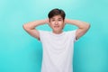 Too loud. Frustrated young man covering ears with hands and looking at camera while standing blue background Royalty Free Stock Photo