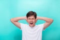 Too loud. Frustrated young man covering ears with hands and looking at camera while standing grey background Royalty Free Stock Photo
