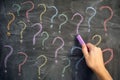 Too many questions. Man drawing colorful question marks on a blackboard Royalty Free Stock Photo