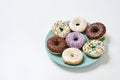 Too much sugar. Freshly baked various delicious colourful round glazed donuts with sprinkles on the plate