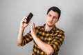 Too much talk. young man in yellow shirt annoyed by a voice on phone, gesturing with one hand against on grey background