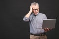 Too much work to do. Tired angry senior aged man with laptop computer isolated against black background Royalty Free Stock Photo