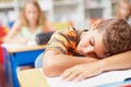 Too tired to concentrate. Young boy sleeping in class with his head on his desk - copyspace.