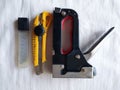 The tool for construction works, the stipler of black color to the white handle connects objects metal brackets, a construction