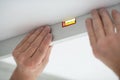 Tool level in men's hands and a flat horizontal surface of the ceiling. Styrofoam, seiling mounting. Royalty Free Stock Photo
