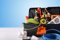 Toolbox full of tools and electrical equipment on white table