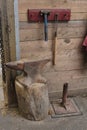 Tools and chains hanging on pegs on a rough wooden wall made of planks next to an anvil in a barn. Royalty Free Stock Photo