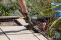 Tools of the craftsman. A professional paver worker laying patio slabs in a gravel bed using a professional paving hammer.