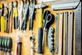 Tools and devices hanging on workshop wall. Rulers, cutting knives, scissors and other objects well arranged in working place. Royalty Free Stock Photo