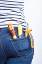 Tools for electrician in back pocket of blue jeans worn by a woman. Screwdriver, cutters and sharp knife.