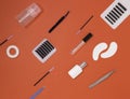 Tools for eyelash extension on an orange background, top view. Artificial eyelashes, tweezers, microbrushes, patches and brushes