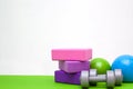 Tools for fitness exercises - pink and purple blocks, balls and dumbbell on green mat. free space for text - gymnastic, stretching