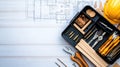 Tools including screwdriver bits and wood dowels are organized in a toolkit, accompanied by construction blueprints on a Royalty Free Stock Photo
