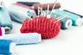 Tools for needlework, red knitted needle pad for sewing and colored thread coils on white background with copy space for text Royalty Free Stock Photo