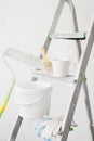 Tools for painting walls: roller, tray, bucket of paint, brush, gloves and a cup of coffee on a stepladder near a white painted Royalty Free Stock Photo