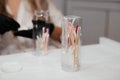 Tools for permanent makeup inside the bottle in focus and blurred hands of female master in black gloves on background.