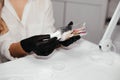 Tools for permanent makeup inside the bottle in hands of female master in black gloves, selective focus.