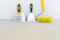 Tools for plastering and painting. Roller brush and putty knife on concrete floor background Royalty Free Stock Photo