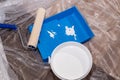 Tools for priming plastered surfaces for further painting.Paint roller in a blue tray with white paint on dirty floor Royalty Free Stock Photo