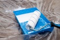 Tools for priming plastered surfaces for further painting.Paint roller in a blue tray with white paint on dirty floor Royalty Free Stock Photo