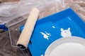 Tools for priming plastered surfaces for further painting.Paint roller in a blue tray with white paint on dirty floor Royalty Free Stock Photo