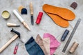 Tools for repairing shoes on grey stone desk background top view