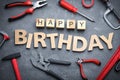 Tools and words HAPPY BIRTHDAY on stone background, flat lay