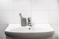 Toot brush cup in bathroom and toilet sink. Toothbrush in clean restroom. Water tap, faucet and basin to wash hands in WC. Royalty Free Stock Photo