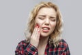 Tooth ache. Portrait of beautiful blonde young woman in casual red checkered shirt standing and touching her painful teeth with