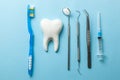 Tooth and dental instruments on blue background. Dental treatment. Dentist tools mirror, hook, tweezers, syringe and toothbrush Royalty Free Stock Photo