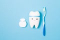 tooth model, plastic toothbrush with blue handle and dental floss in a white container on a blue background, copy space, top view Royalty Free Stock Photo