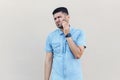 Tooth pain. Portrait of worry sad handsome young bearded man in blue shirt standing, touching his cheek because feeling toothache