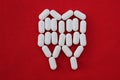 Tooth from pills on a red background. Dental clinic concept. Calcium vitamin in the form of a tooth spilled out on a red backgroun