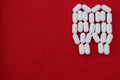 Tooth from pills on a red background. Dental clinic concept. Calcium vitamin in the form of a tooth spilled out on a red backgroun