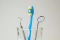 Toothbrush blue and dental tools mirror and hook in glass. Dental care and visit to dentist