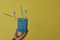 Toothbrush container set with toothbrushes and soap on the hand of a woman on yellow background with copy space