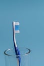 Toothbrush, in a glass on blue background. vertical photo Royalty Free Stock Photo