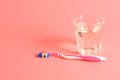 Toothbrush and a glass of water on a pink background Royalty Free Stock Photo