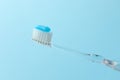 Toothbrush with toothpaste in air on light blue background, closeup Royalty Free Stock Photo