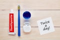 Toothbrush, toothpaste, dental floss and mouthwash with a twice a day note on wooden table Royalty Free Stock Photo