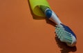 2 toothbrushes, blue and pink. Isolated on green and orange background. Royalty Free Stock Photo