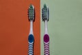 2 toothbrushes, blue and pink. Isolated on green and orange background. Royalty Free Stock Photo