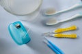 Toothbrushes, dental floss, interdental brushes and a glass of medicated mouthwash on white background