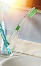 Toothbrushes in a glass cup on a sink vertical Royalty Free Stock Photo