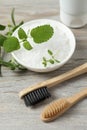 Toothbrushes, green herbs and sea salt on wooden table, above view