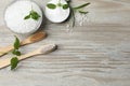 Toothbrushes, green herbs and sea salt on wooden table, flat lay. Space for text