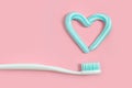 Toothbrushes and turquoise color toothpaste in shape of heart on pink background. Dental and healthcare concept. Royalty Free Stock Photo